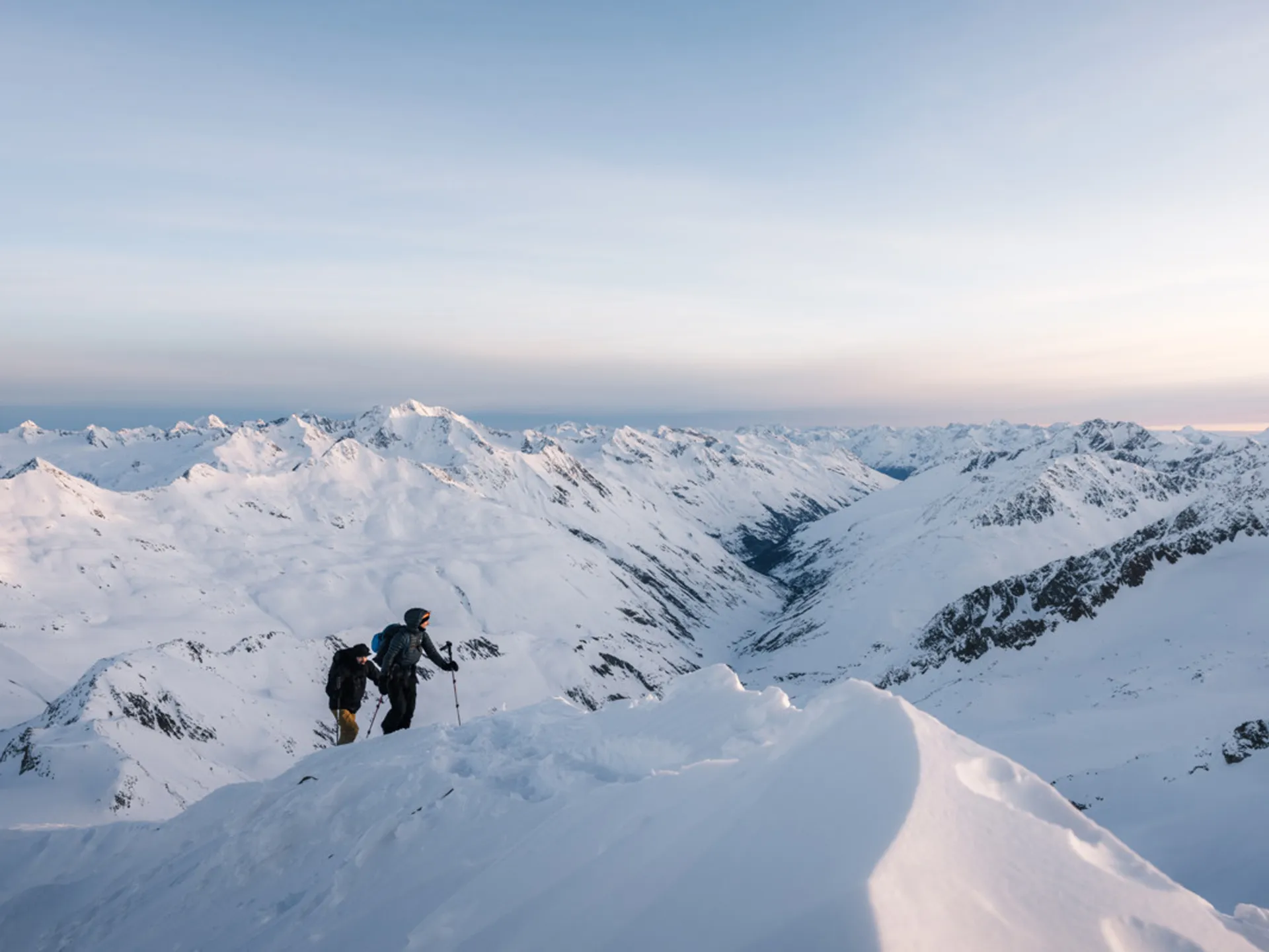 Weisskugel: dein Gasthof in Vent Zwei Wanderer besteigen schneebedeckten Berg mit Alpenpanorama bei Sonnenuntergang