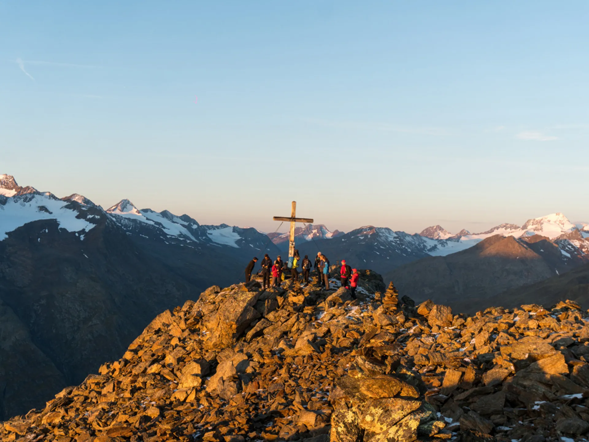 Gasthof Weisskugel: your walking holiday in the Austrian Alps Group of hikers on rocky mountain summit with cross at sunset