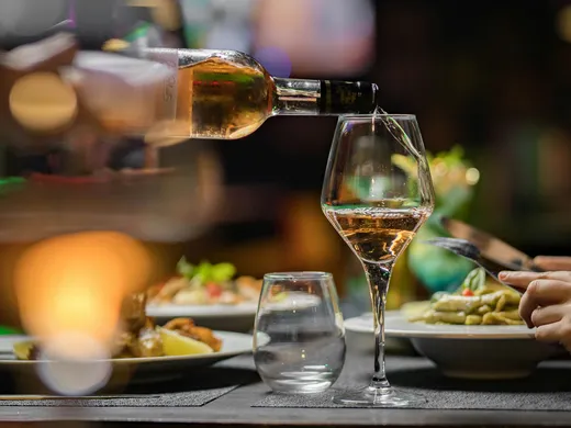 Weisskugel: dein Gasthof in Vent Wein wird in ein Glas am gedeckten Restauranttisch eingeschenkt