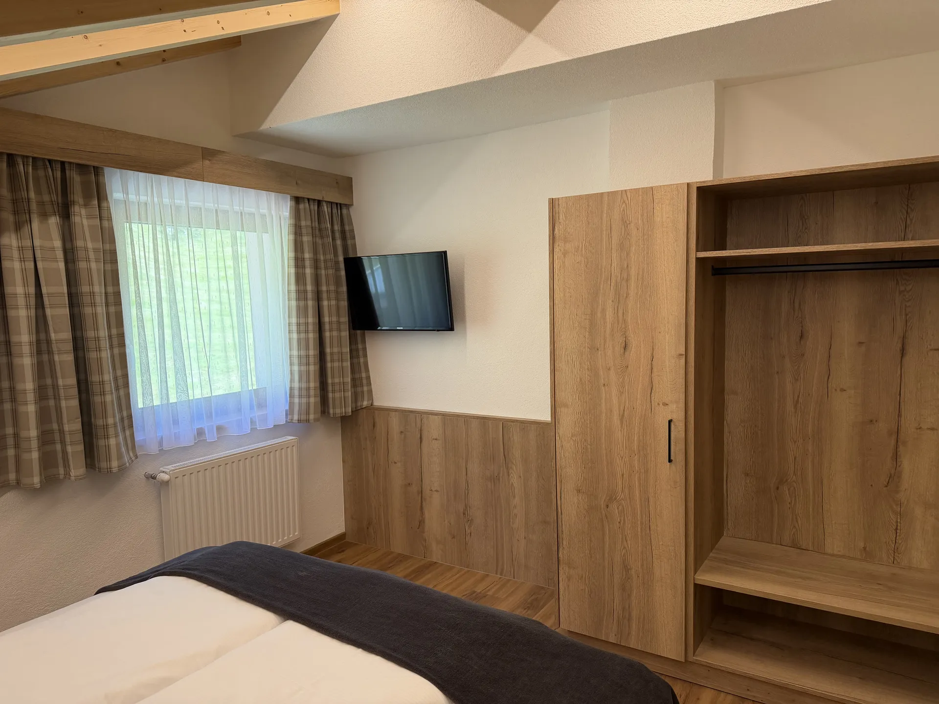 Weisskugel: dein Gasthof in Vent Schlafzimmer mit Bett, Fernseher, Fenster und offenem Holzkleiderschrank