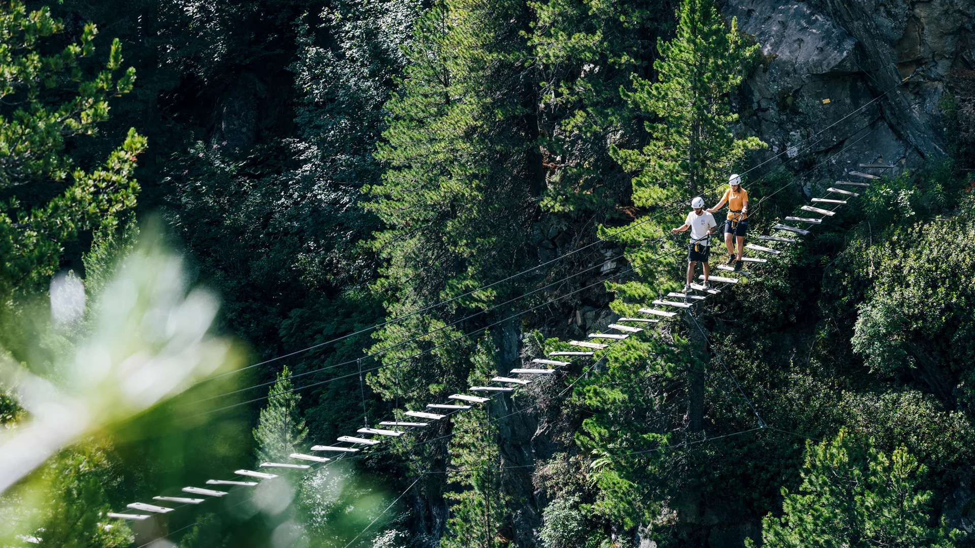 Gasthof Weisskugel: your walking holiday in the Austrian Alps Zwei Personen gehen auf einer Hängebrücke aus Holz über einen bewaldeten Abgrund