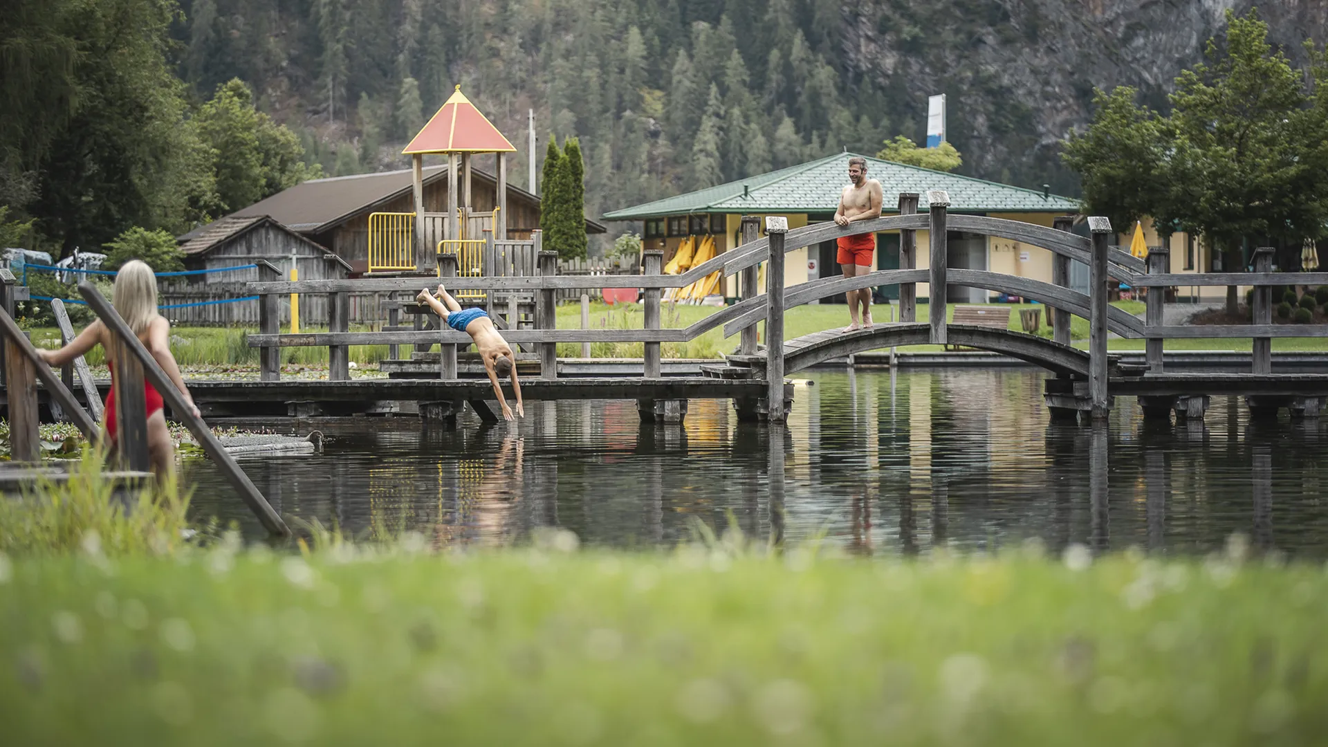 Gasthof Weisskugel: your walking holiday in the Austrian Alps Mann springt von Holzbrücke in See, andere Personen am Ufer und auf Brücke