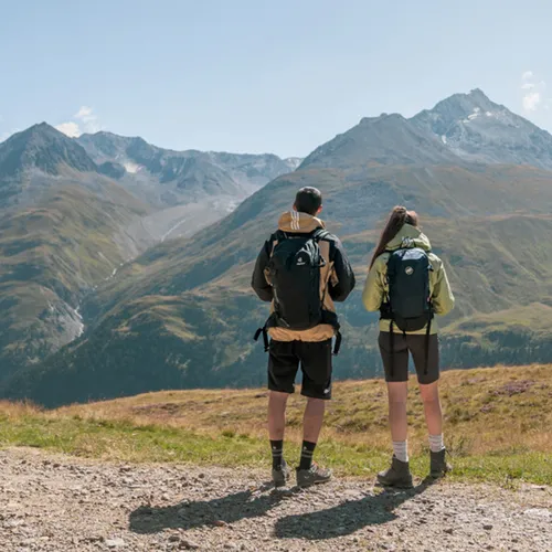 Gasthof Weisskugel: your walking holiday in the Austrian Alps Zwei Wanderer mit Rucksäcken blicken auf Berglandschaft bei klarem Himmel