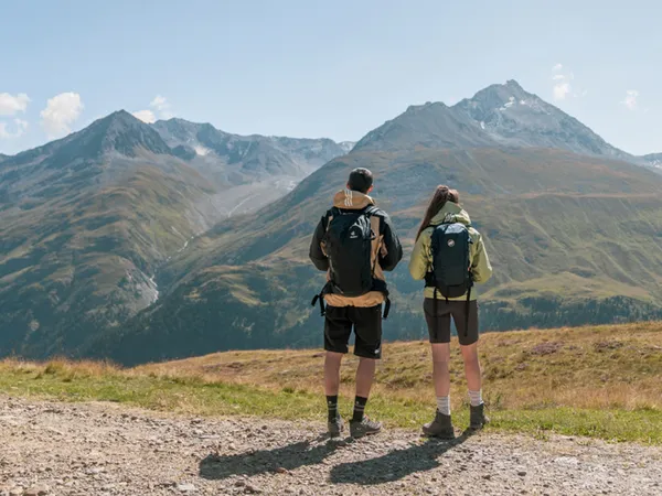 Gasthof Weisskugel: your walking holiday in the Austrian Alps Zwei Wanderer mit Rucksäcken blicken auf Berglandschaft bei klarem Himmel