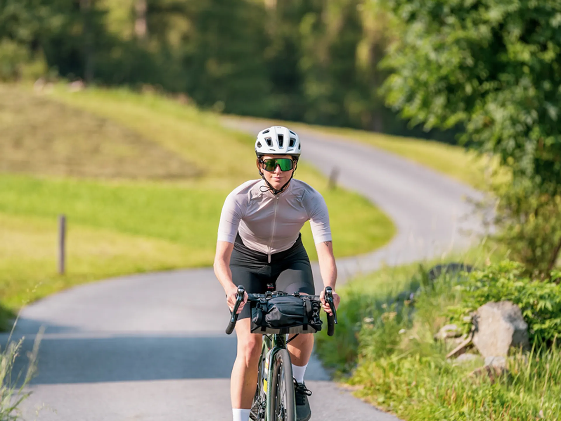 Weisskugel: dein Gasthof in Vent Frau fährt Fahrrad auf kurviger Landstraße umgeben von grüner Natur